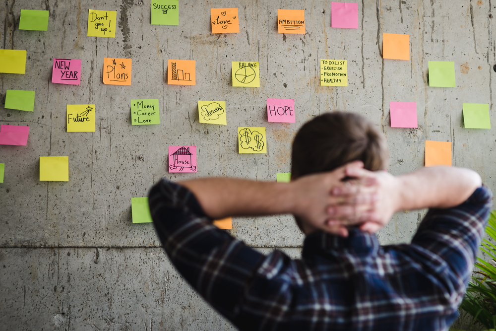 Entrepreneur looking at sticky notes on a wall.