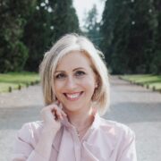 Blonde haired woman standing in a park.