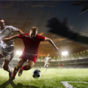 Soccer players in action on the sunset stadium background panorama.