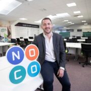 Man sitting on desk in office.