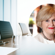 Smiling woman inset on image of a boardroom table.