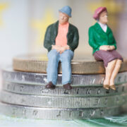 Man and woman on stack of euro coins.