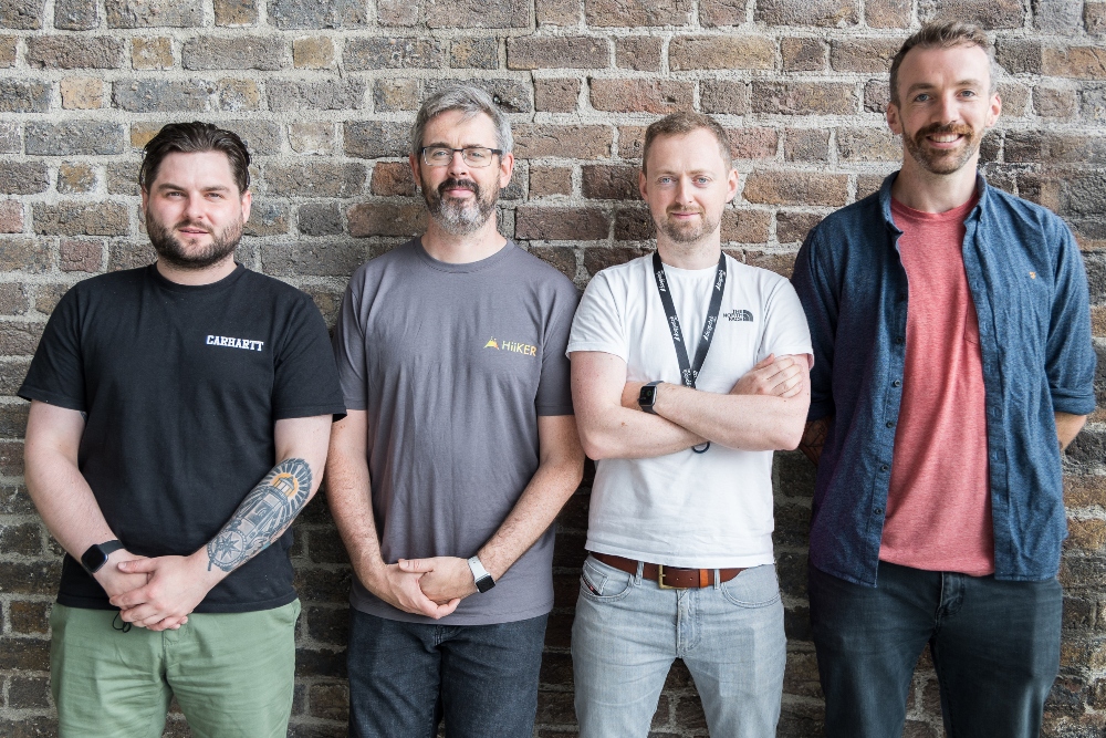Four men in front of a brick wall.