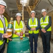 Man in hard hat holding a bottle of whiskey.
