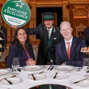 Hotel staff with man and woman, seated.