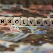 insolvency spelled on dice on top of cash and coins.