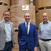 three men in front of brown paper rolls.