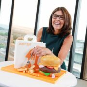Woman behind bag of takeaway food items.