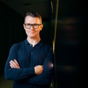 Man with arms folded, navy sweater.