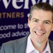 Smiling man in grey jacket.