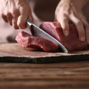 Butcher cutting raw meat.