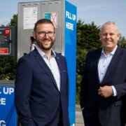 Two men in front of a fuel pump.