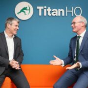 Two men sitting on an orange couch.