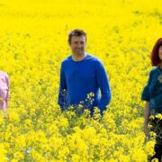 Two men and a woman standing in a field.