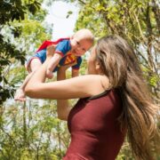 Woman holding child dressed in superman outfit.