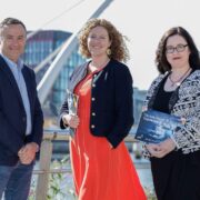 Man and two women near a bridge in Dublin on a sunny day.