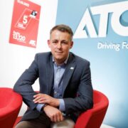 Man in blazer sitting in a red chair.
