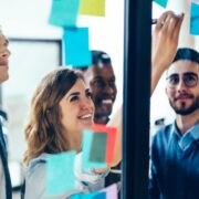 Group of colleagues putting stickies on a glass wall.