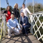 A group of men and women on a white foot bridge.