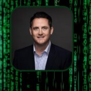 Dark-haired man in suit inset on image of digital code.