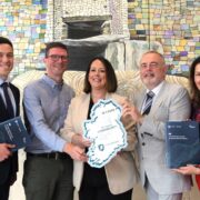 Three men and a woman holding an image of Ireland.