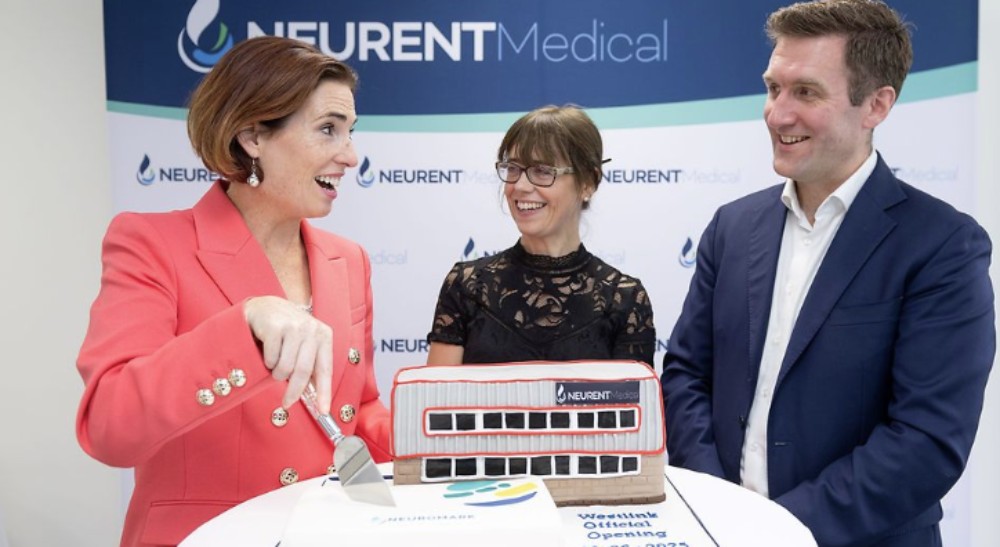 Woman cutting a cake beside man and woman.