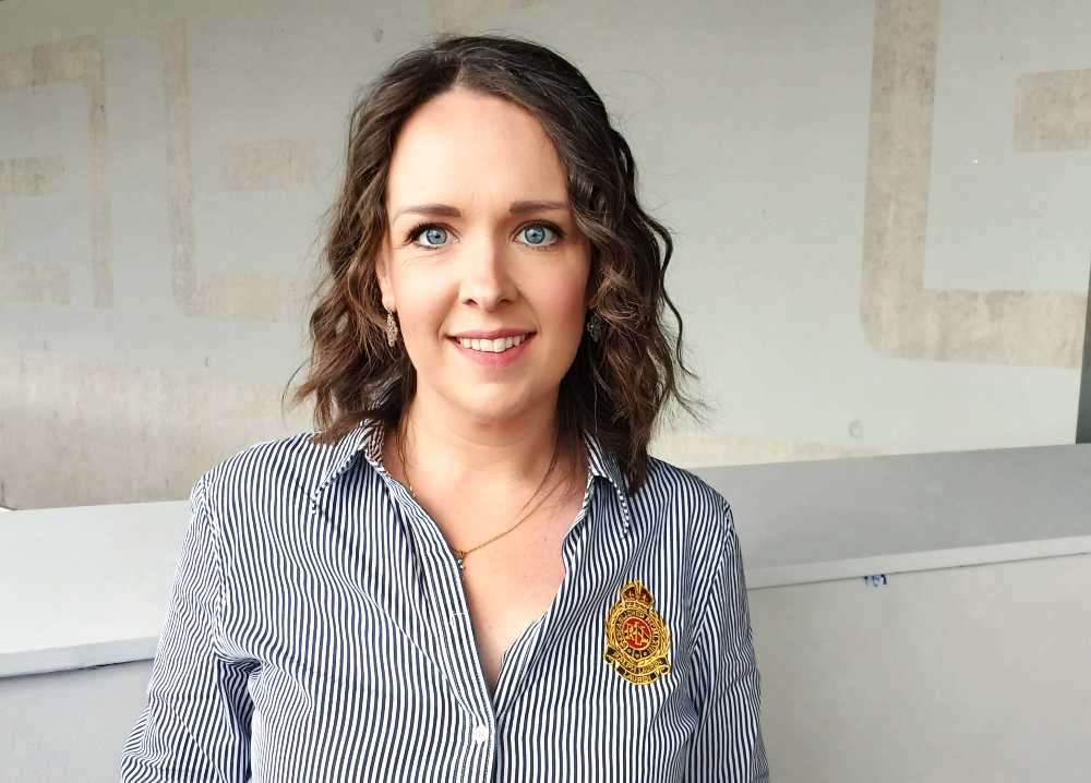Young woman with brown hair wearing striped blouse.