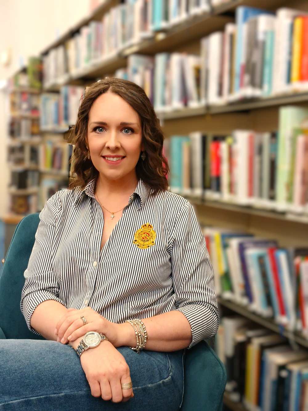 Woman in stripy blouse sitting in a library.