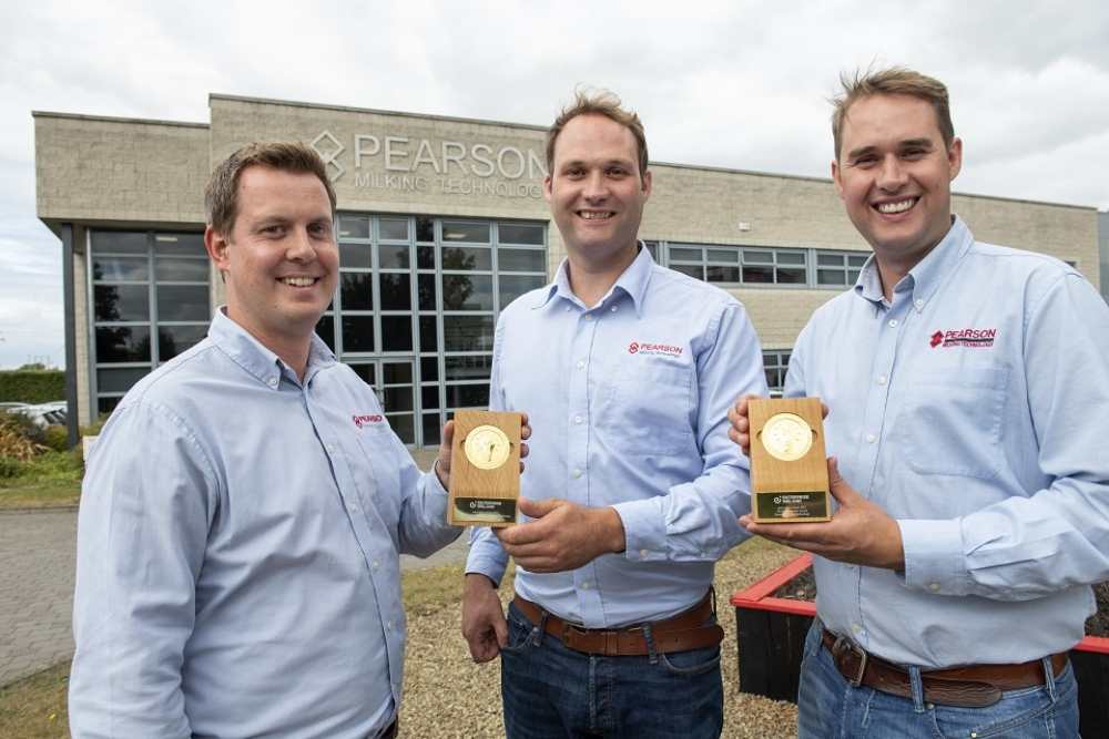 Three men in blue shirts holding prizes.