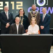 Group of male and female dignitaries signing an agreement.