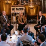 Two men and a woman speaking on stage.