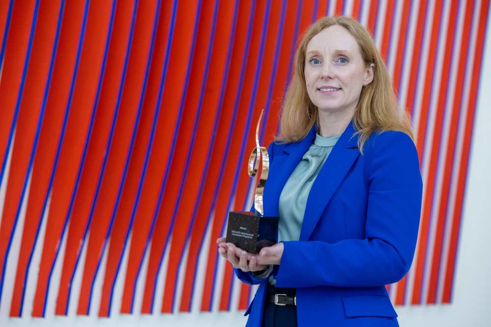 Woman in blue suit holding an award.