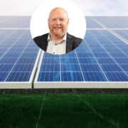 Portrait of a business leader overlaid on a background of large solar panels at a ground-mounted solar energy site in Ireland.